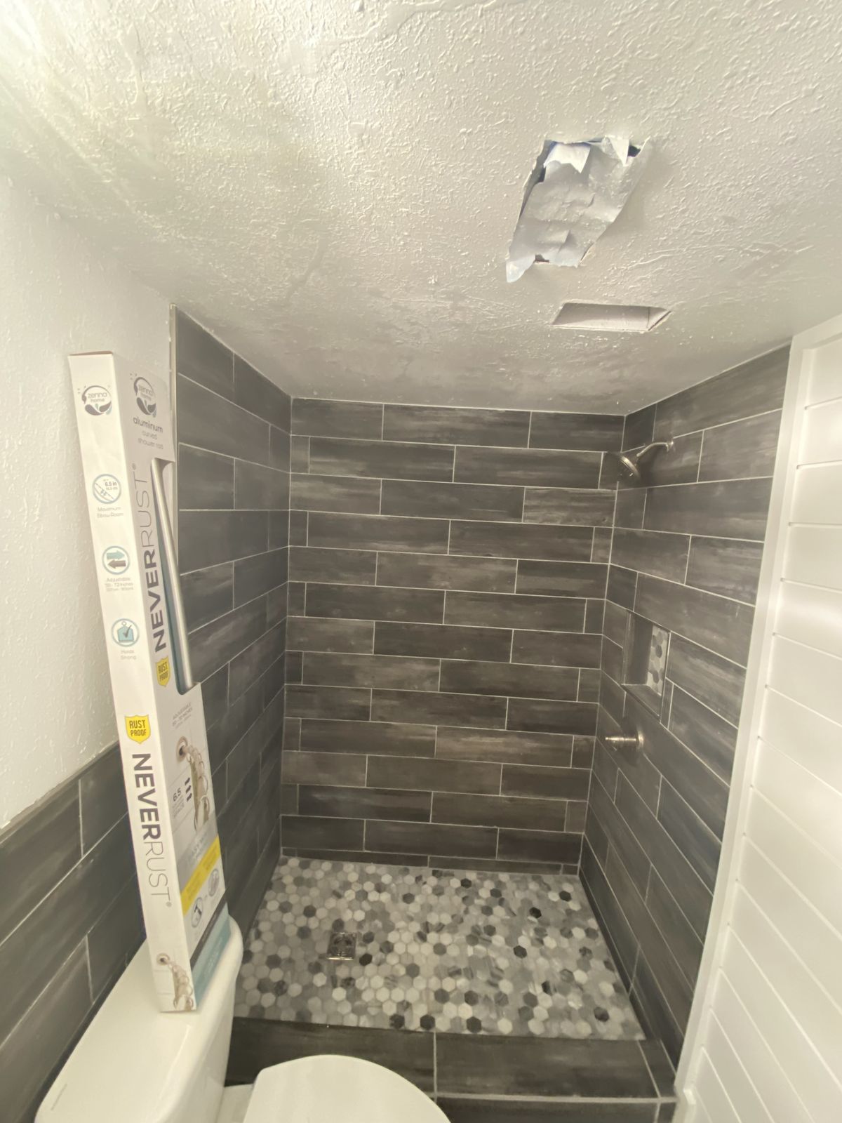 Gray plank tile shower with pebble floor