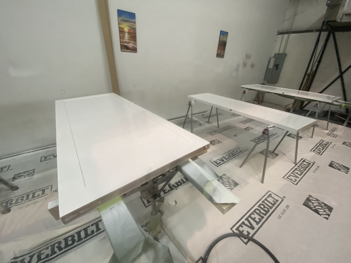 Freshly painted white cabinet panels drying in the spray booth